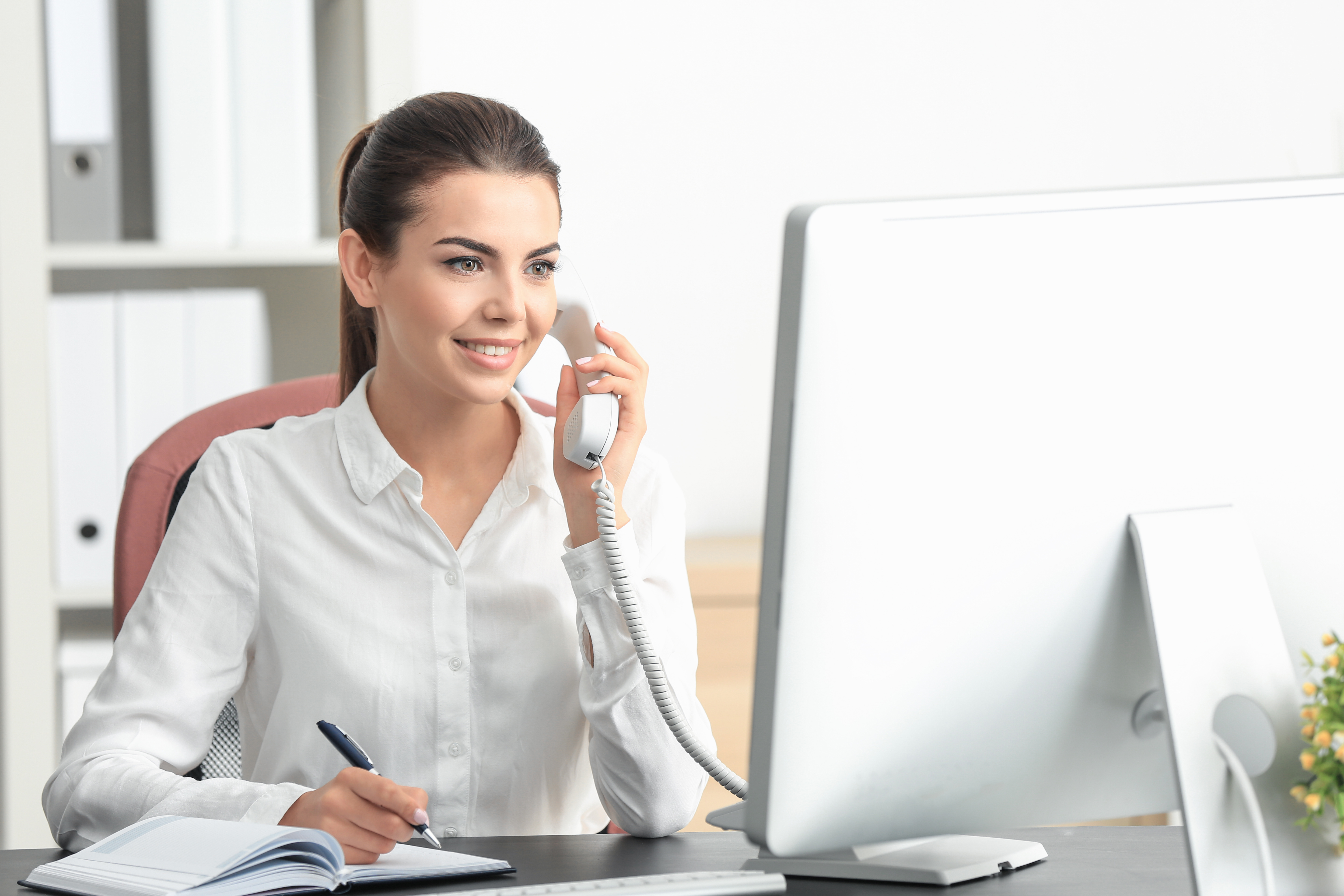 Young female receptionist talking on phone in office Young female receptionist talking on phone in office