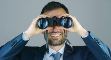 A businessman in a suit and tie, use the binoculars to look away with the concept of looking to the future, forecasting the economic and financial growth and the future