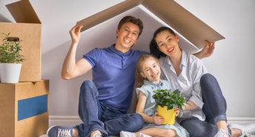 Mother, father and child girl in the house with a symbol of roof. Concept of housing for young family.